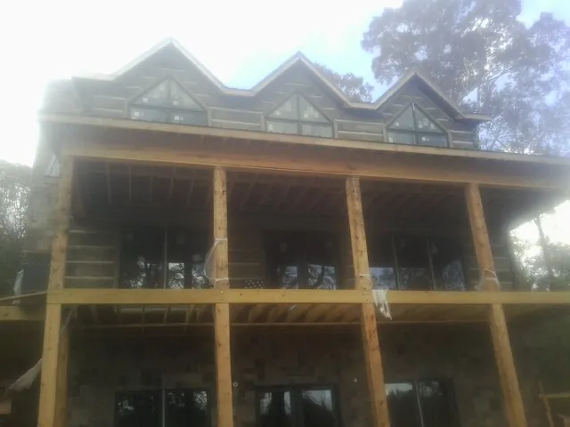 Dormers and porch framing on a large log home under construction — Roof Coating work by our crew in Vincent