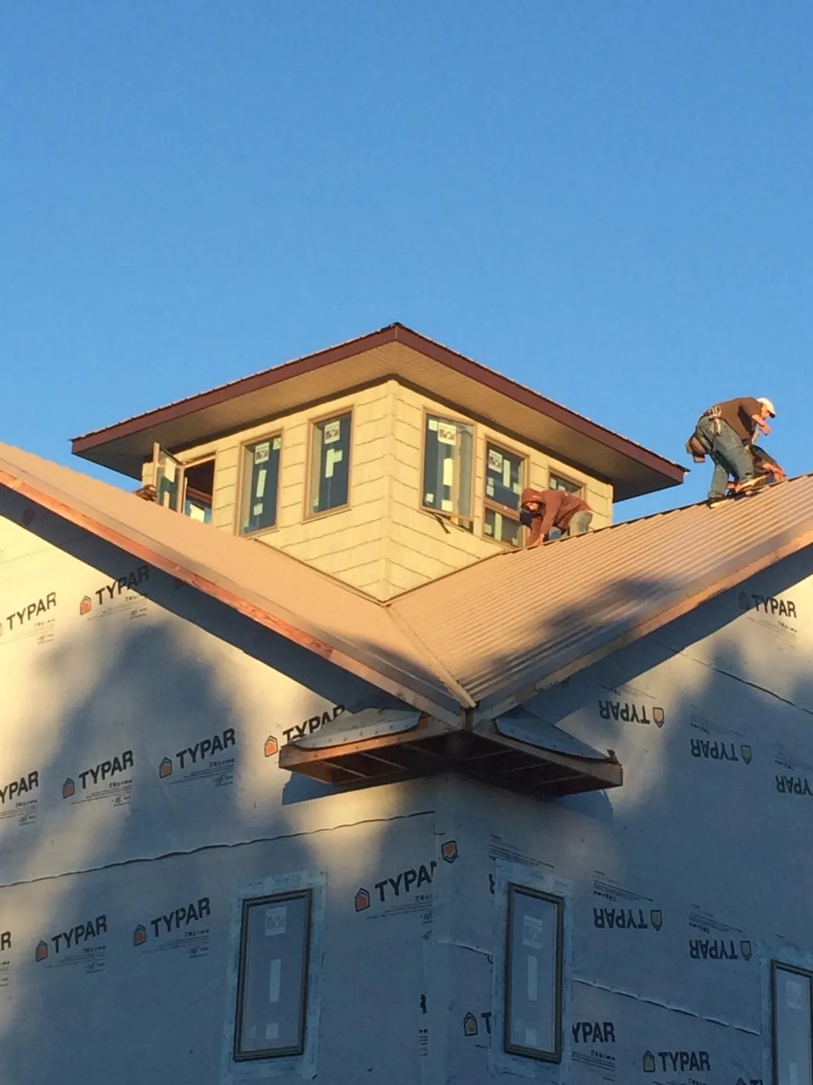Roofers working around a rooftop cupola on a new metal roof at sunset — Roof Waterproofing in Vincent by Roofing Brothers